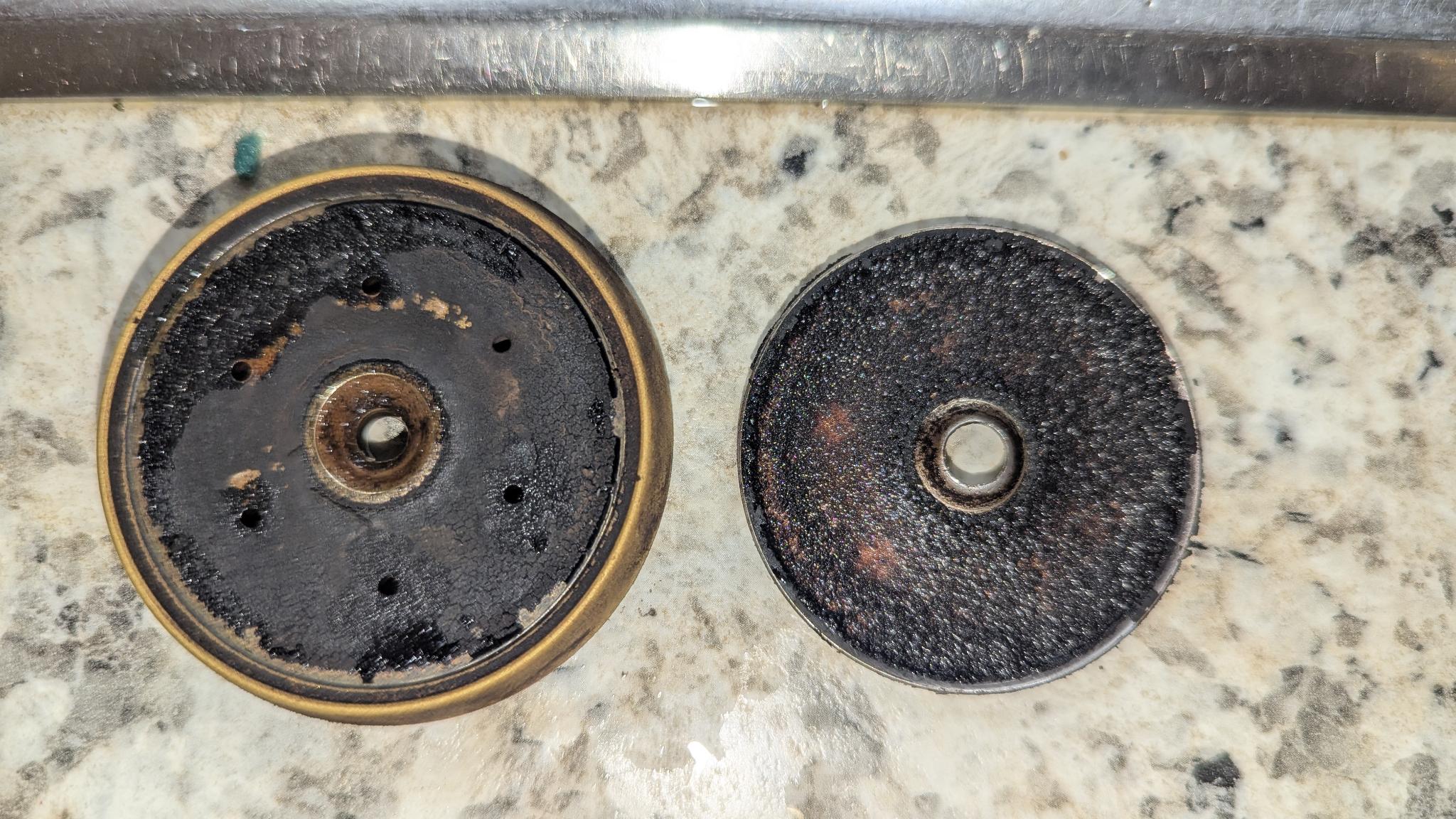 A pic of an espresso machine diffusor and a shower screen with a thick layer of coffee residue blocking all holes